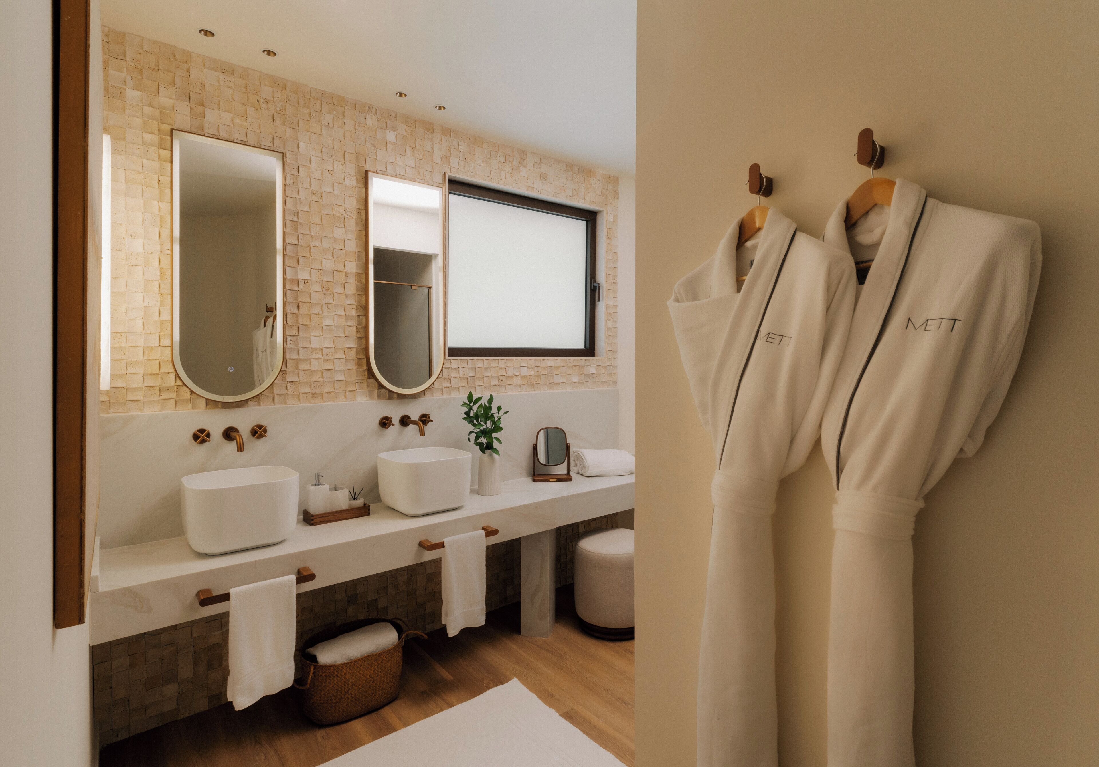 Une salle de bain moderne avec un grand miroir, deux lavabos et un porte-peignoir.