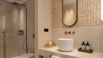 A modern bathroom with a large mirror, a white sink, and a shower area.