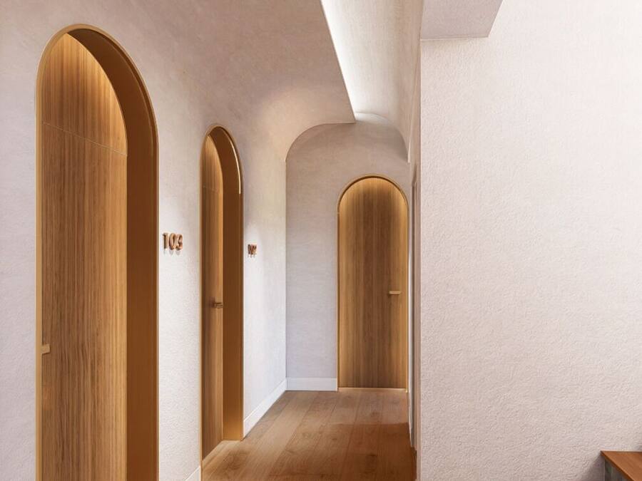 Un pasillo con puertas de madera, una escalera y un revestimiento de pared con textura.