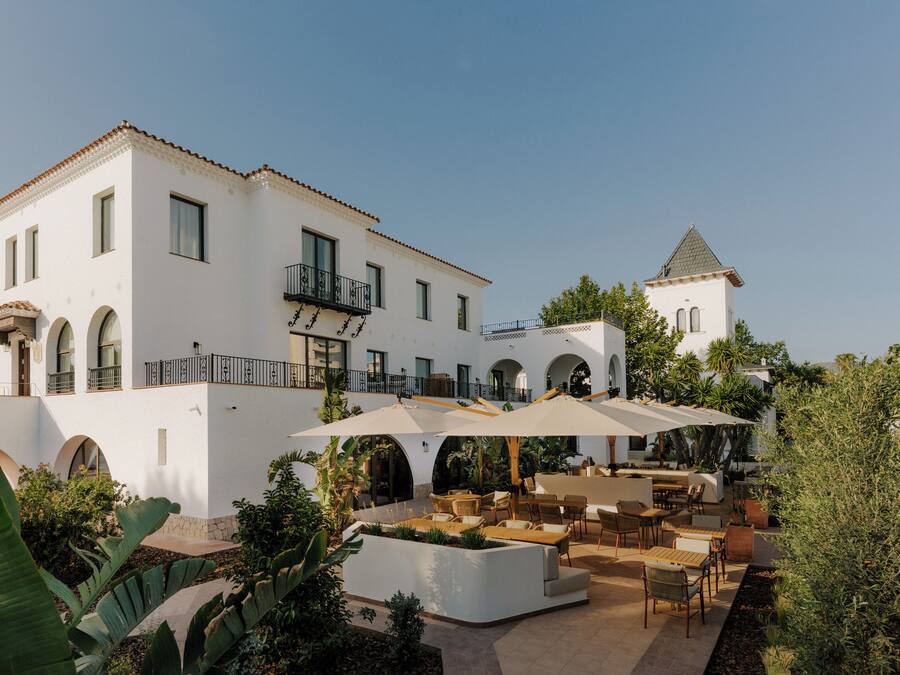 A white building with a balcony and a smaller tower.
