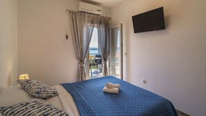 Ein Schlafzimmer mit Bett, Fernseher, Klimaanlage und Blick ins Freie.