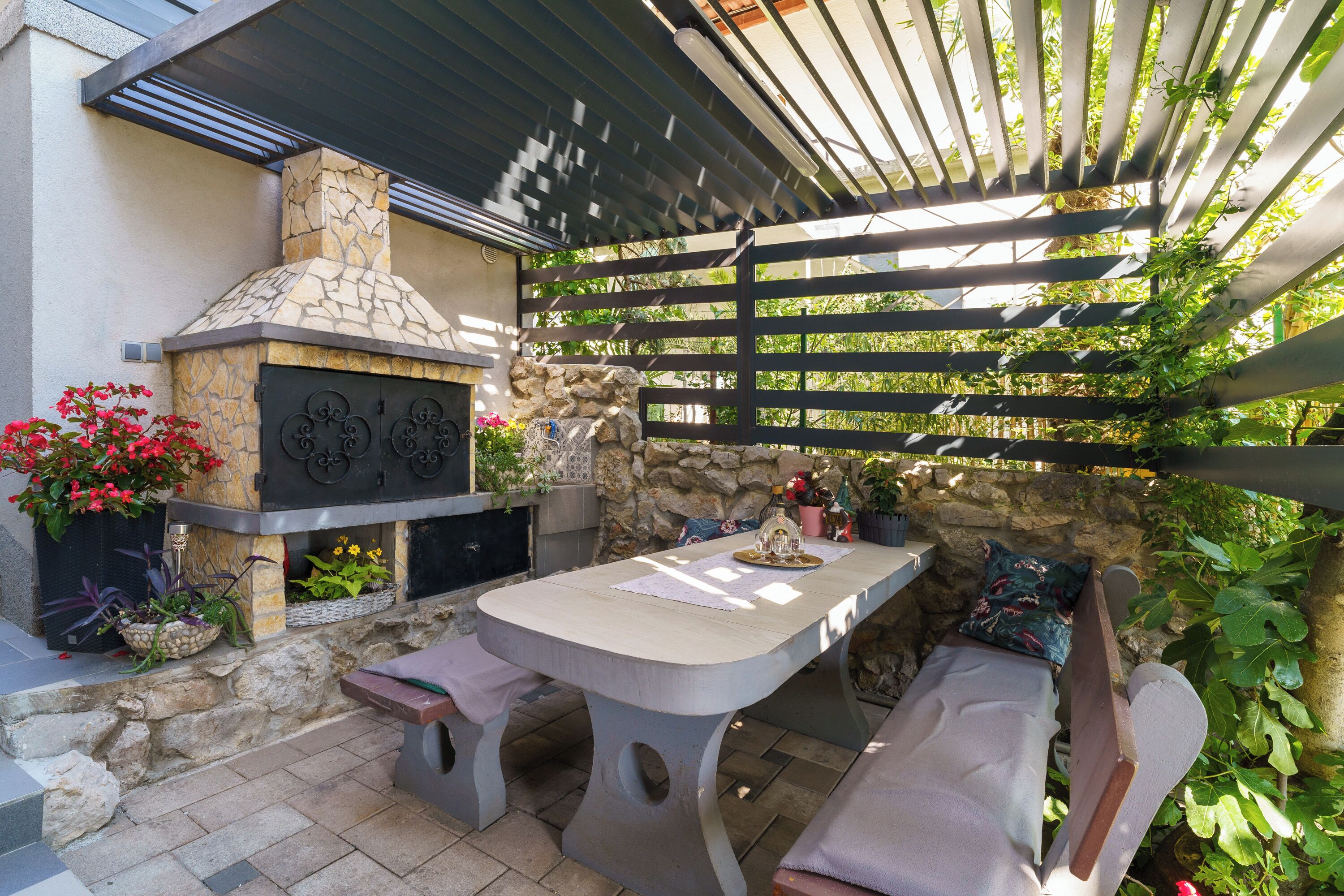 Un patio al aire libre con una chimenea de piedra, una mesa y bancos.