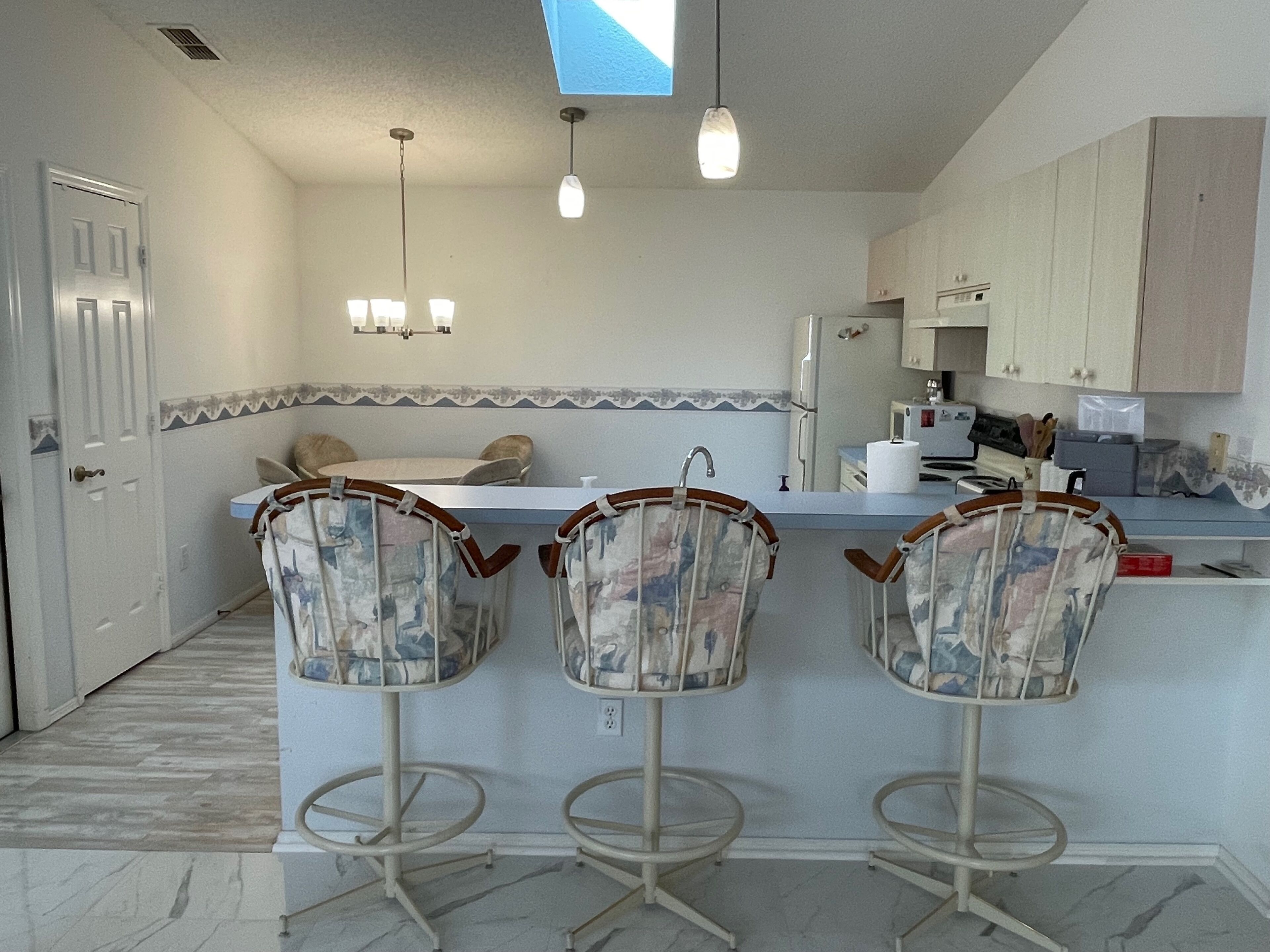A kitchen with a bar area, a refrigerator, and a microwave.