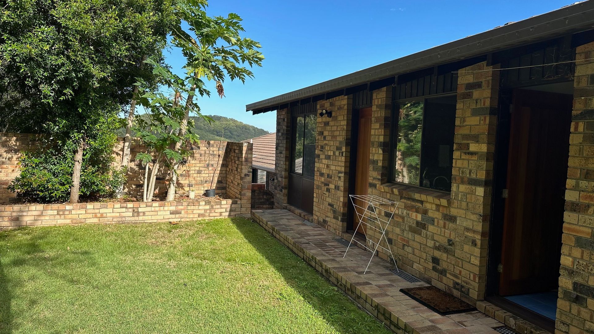A residential property with a brick exterior, a covered patio, and a well-maintained lawn.