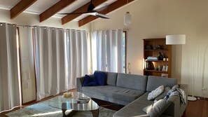 A living room with a grey sofa, a glass coffee table, and a bookshelf.