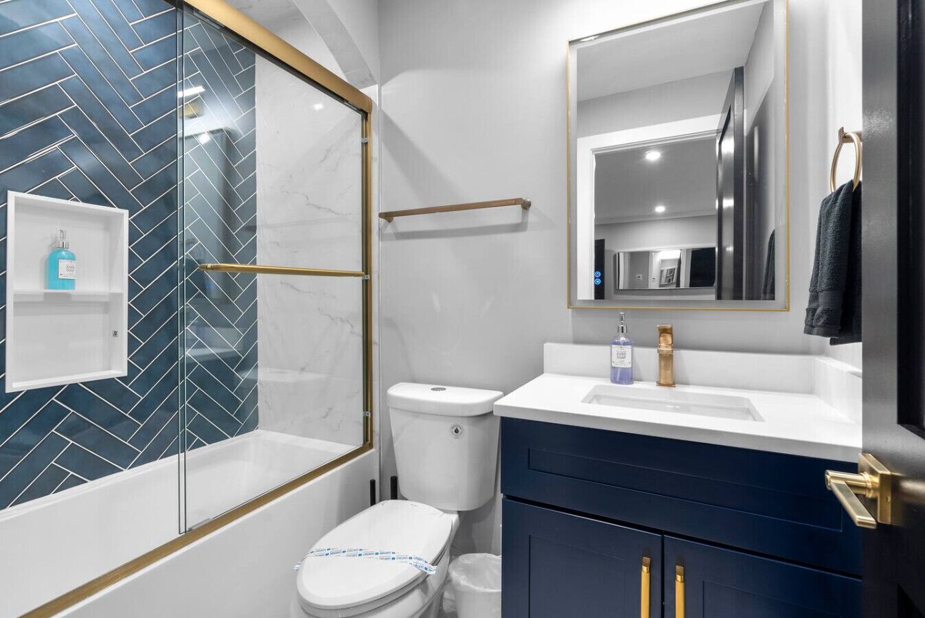 A modern bathroom with a glass-enclosed shower, a white toilet, a vanity with a sink, and a mirror.