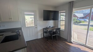 Cozinha compacta com área de refeições, TV de tela plana e vista para o exterior.