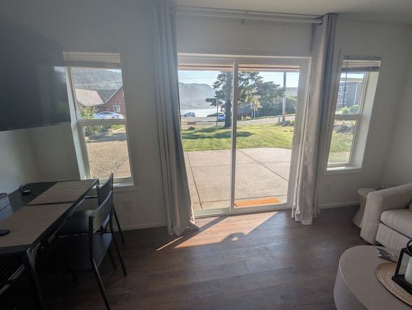 Una habitación con una mesa de comedor, sillas, un sofá y ventanas grandes con cortinas.