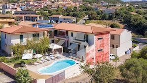 Un edificio residenziale con piscina, diversi balconi e vista su una cittadina collinare.