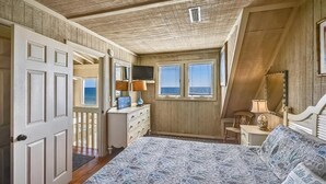Een slaapkamer met een groot bed, een dressoir, een televisie en een raam met zonwering.