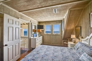 A bedroom with a large bed, a dresser, a television, and a window with blinds. - Welcome to The Ruby Pearl! (St. George Island)