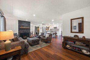 Ein geräumiges Wohnzimmer mit Kamin, Essbereich und einer Küche im Hintergrund.
