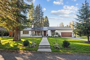 Ein Bungalow mit Veranda, Garage und einem gepflegten Rasen.