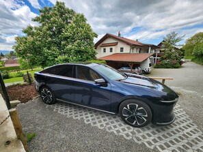 Eine dunkelblaue Limousine steht auf einem gepflasterten Weg, im Hintergrund ein Haus.