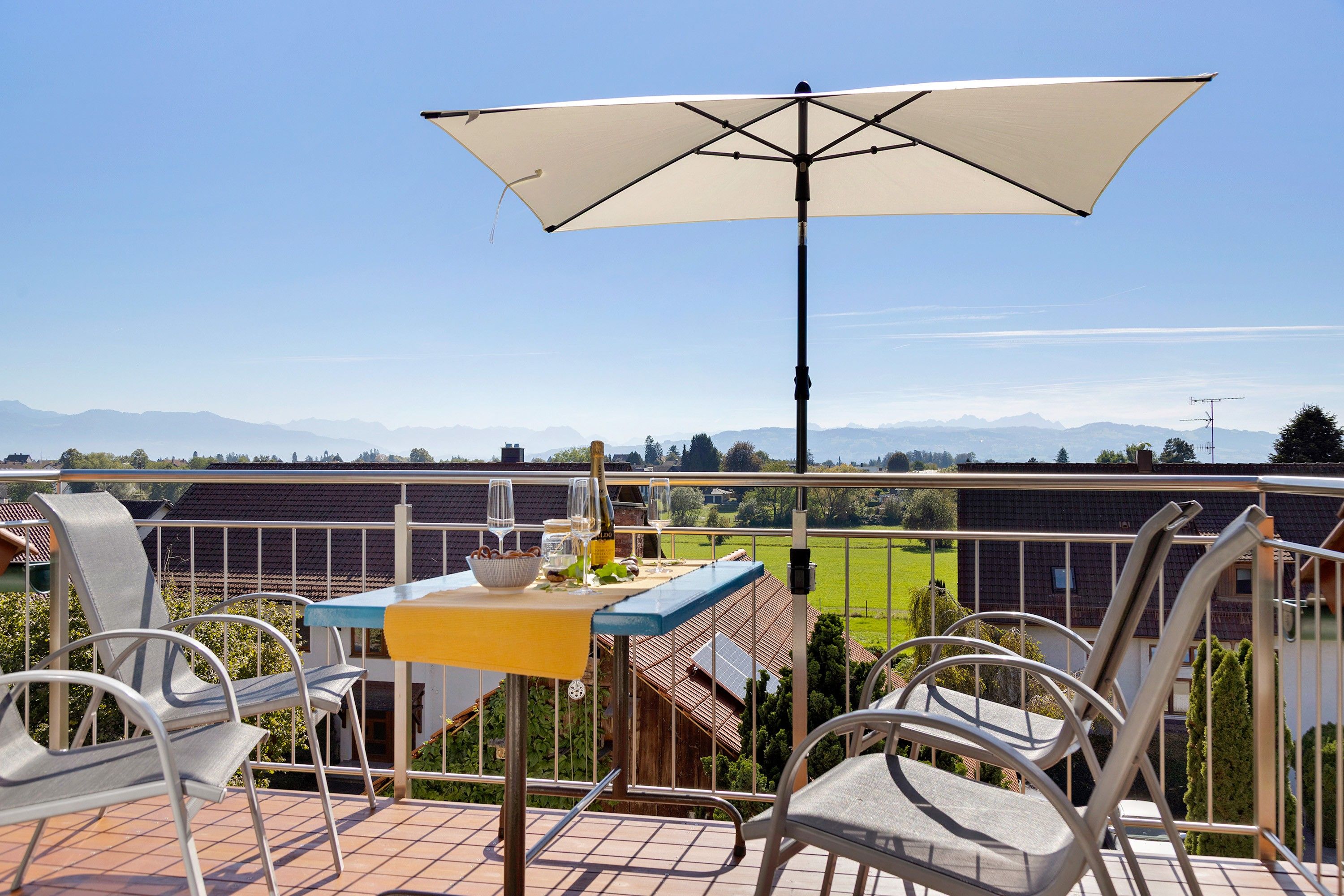 A terrace with a table, chairs, and an umbrella.