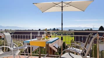 A terrace with a table, chairs, and an umbrella.
