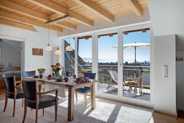 Un comedor moderno con una mesa de madera, sillas y vistas al exterior.