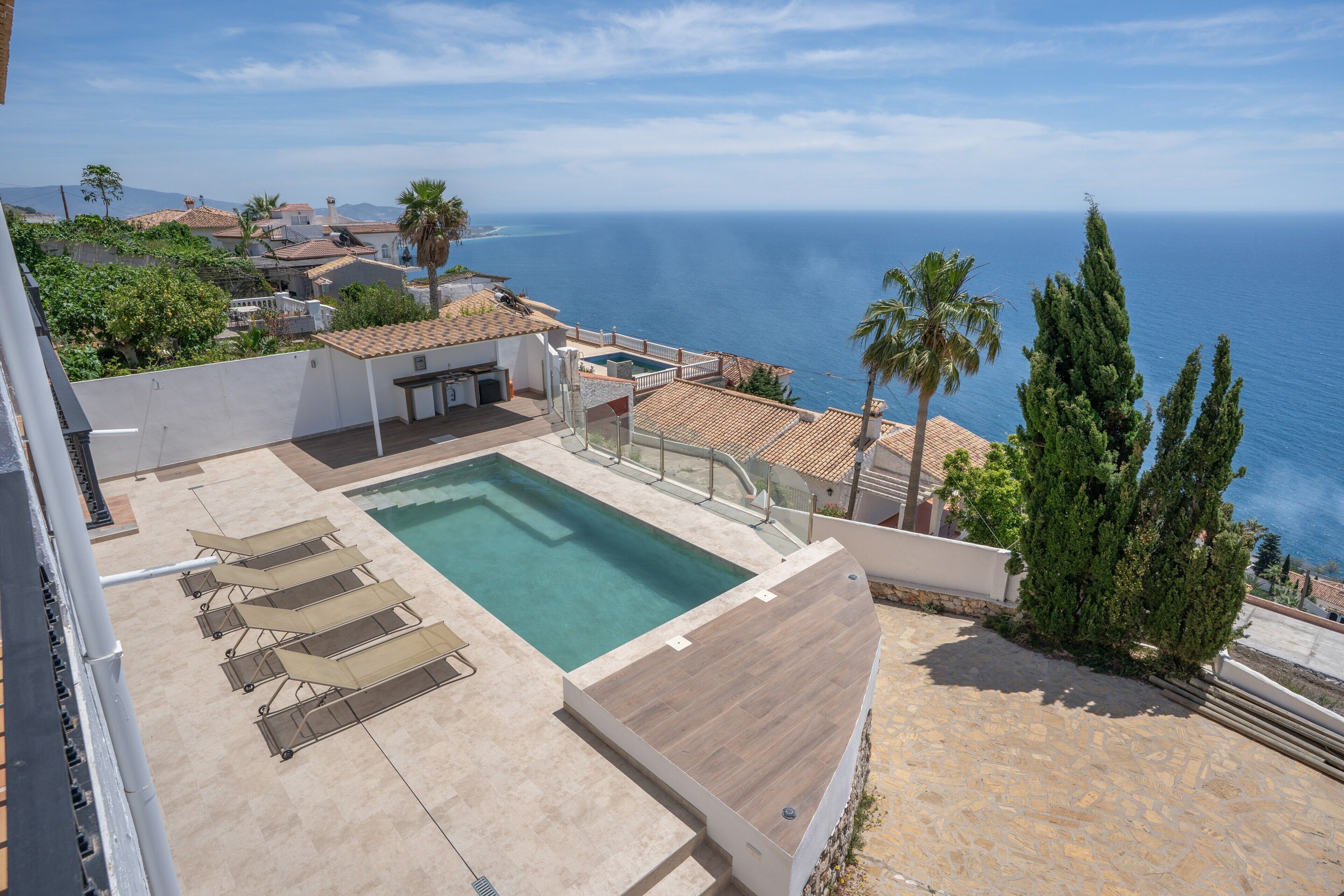 Ein Pool auf dem Dach mit Liegestühlen, einem kleinen Tisch und Blick aufs Meer.