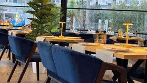A restaurant with tables, chairs, and a large window overlooking a cityscape. - Vila Lira (Durres)