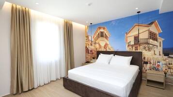 A hotel room with a large bed, beige curtains, a mural of buildings, and a wooden floor.
