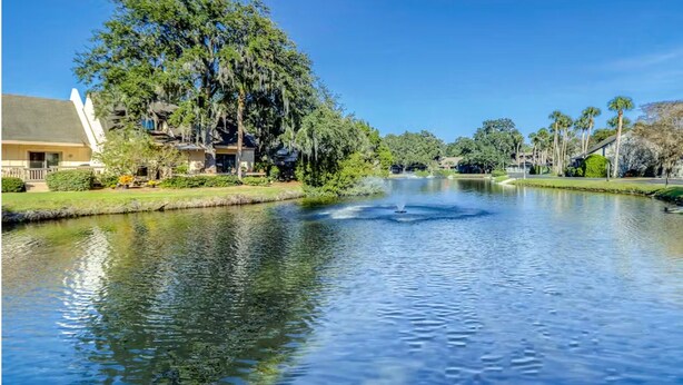 A calm lake with a fountain, surrounded by trees and houses. - Palmetto Dunes Beach Villa | Golf, Pool,  Dogs OK (Hilton Head Island)