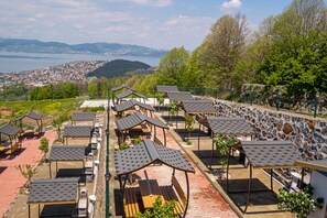 A terrace with multiple tables and benches, overlooking a scenic view of a lake and distant town. - Lale Saray - Sapanca (Sapanca)