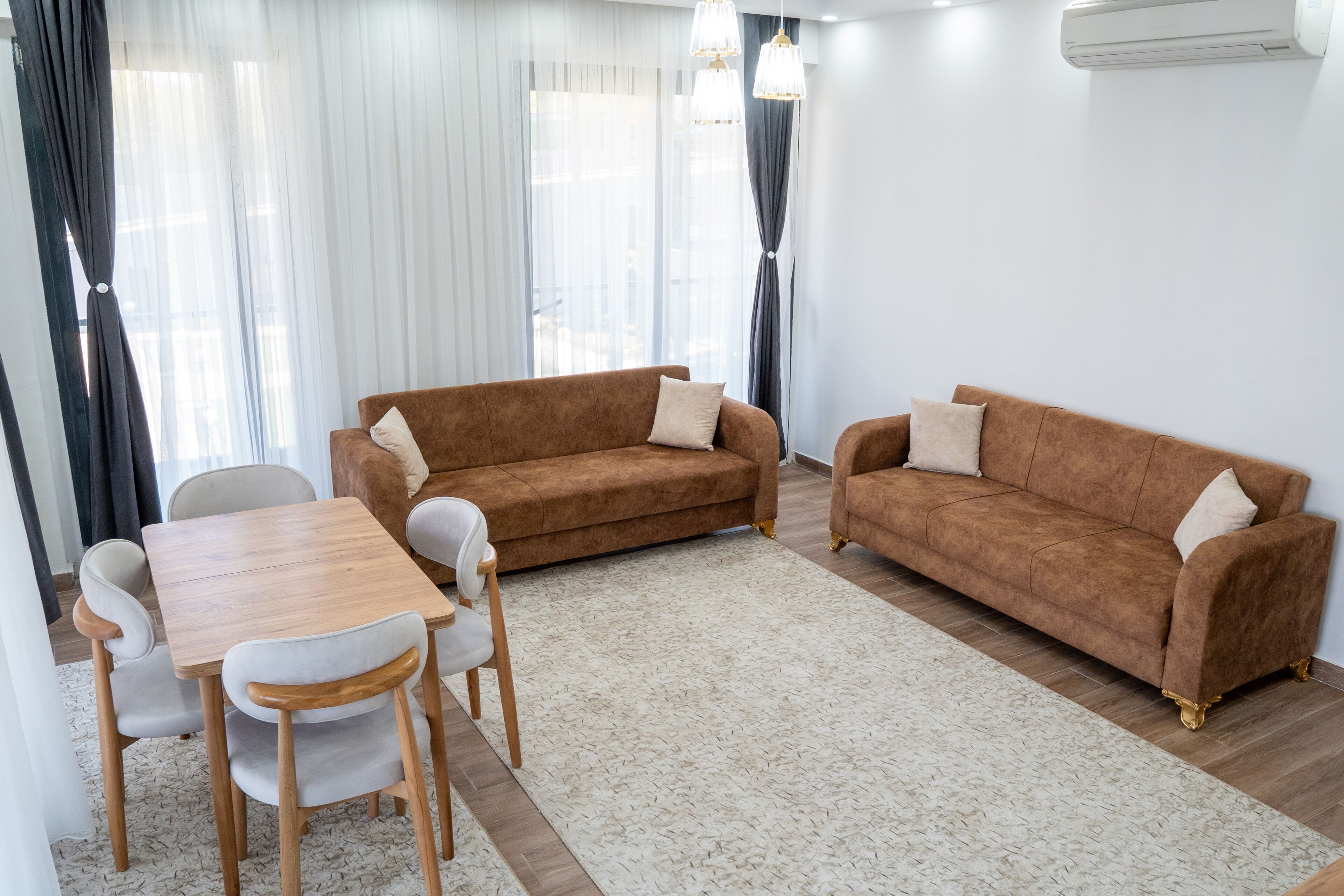A living room with a brown sofa, a wooden coffee table, and a white rug.