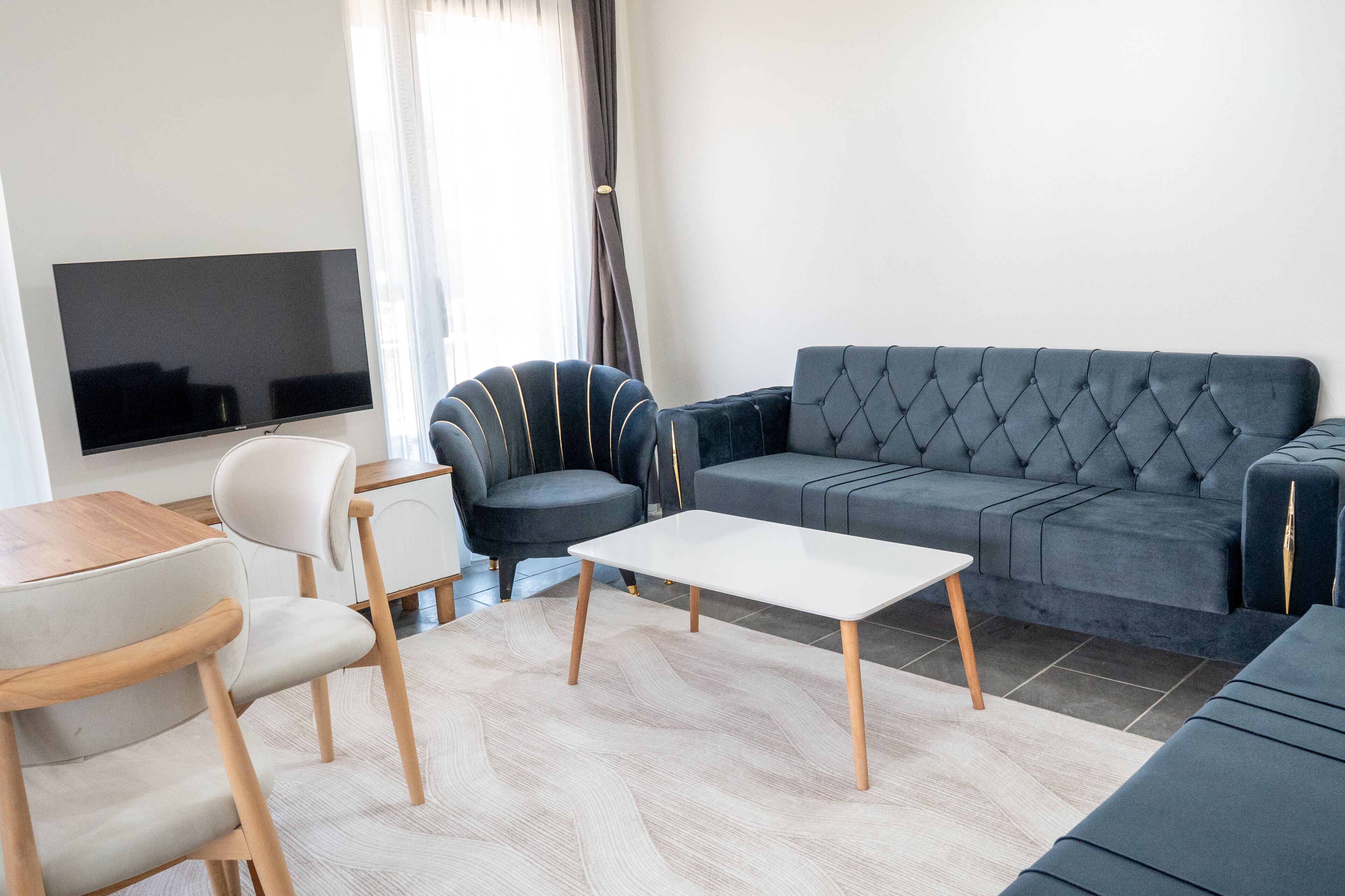 Ein modernes Wohnzimmer mit Flachbildfernseher, grauem Sofa, weißem Couchtisch und grauem Sessel.
