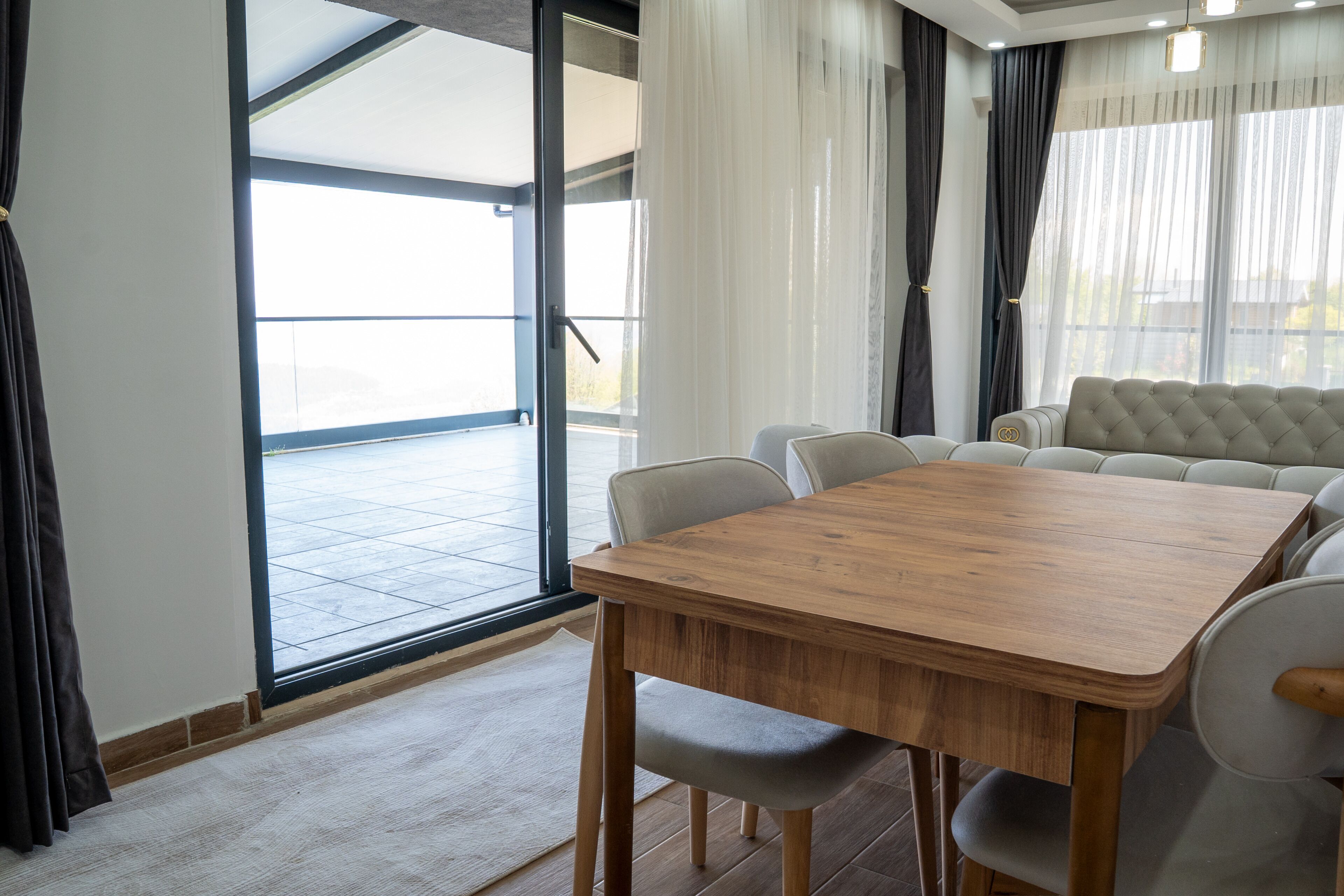 Ein Essbereich mit Holztisch und Stühlen, einer Couch und Blick durch eine Glastür.