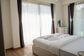 Un dormitorio con cama, cómoda y ventana con cortinas.