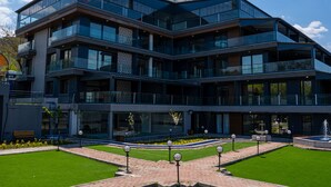 A modern multi-story building with large glass windows, a landscaped garden with a fountain, and a clear blue sky. - Lale Saray - Sapanca (Sapanca)
