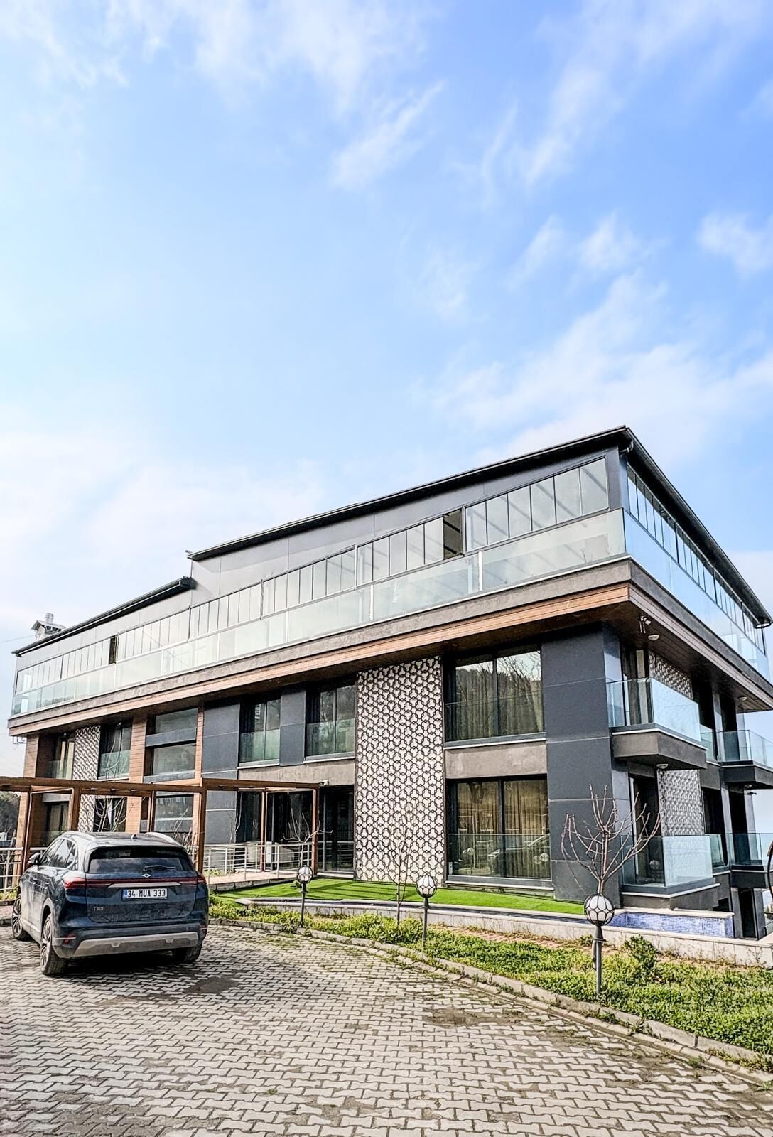 Un bâtiment moderne doté d’un toit plat, de grandes fenêtres et d’une allée pavée.
