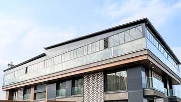 Un edificio moderno con techo plano, ventanas amplias y camino de entrada pavimentado.