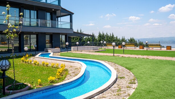 A modern two-story building with a swimming pool, outdoor seating, and a view of the mountains. - Lale Saray - Sapanca (Sapanca)