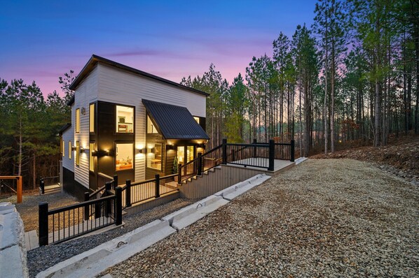 Uma casa moderna com escada, deck e entrada com calçamento de brita.