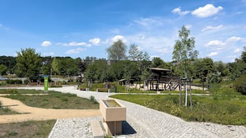 Ein Park mit einem Spielplatz, einem Wasserspiel und einem gepflasterten Weg.