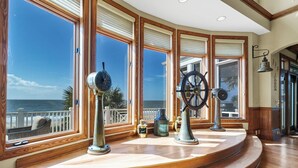 Une pièce dotée de grandes fenêtres, d’une terrasse en bois et d’une décoration sur le thème de la marine.