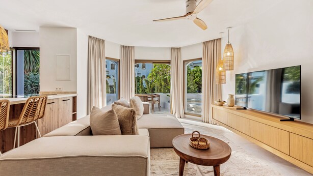 A modern living room with a sofa, TV, and dining area. - Beachside living in a charming urbanisation (Marbella)