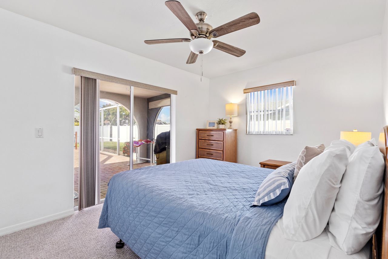 A bedroom with a bed, a ceiling fan, a dresser, and a window.