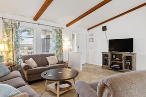 Ein Wohnzimmer mit Sofa, Couchtisch, TV-Schrank und Vorhängen.