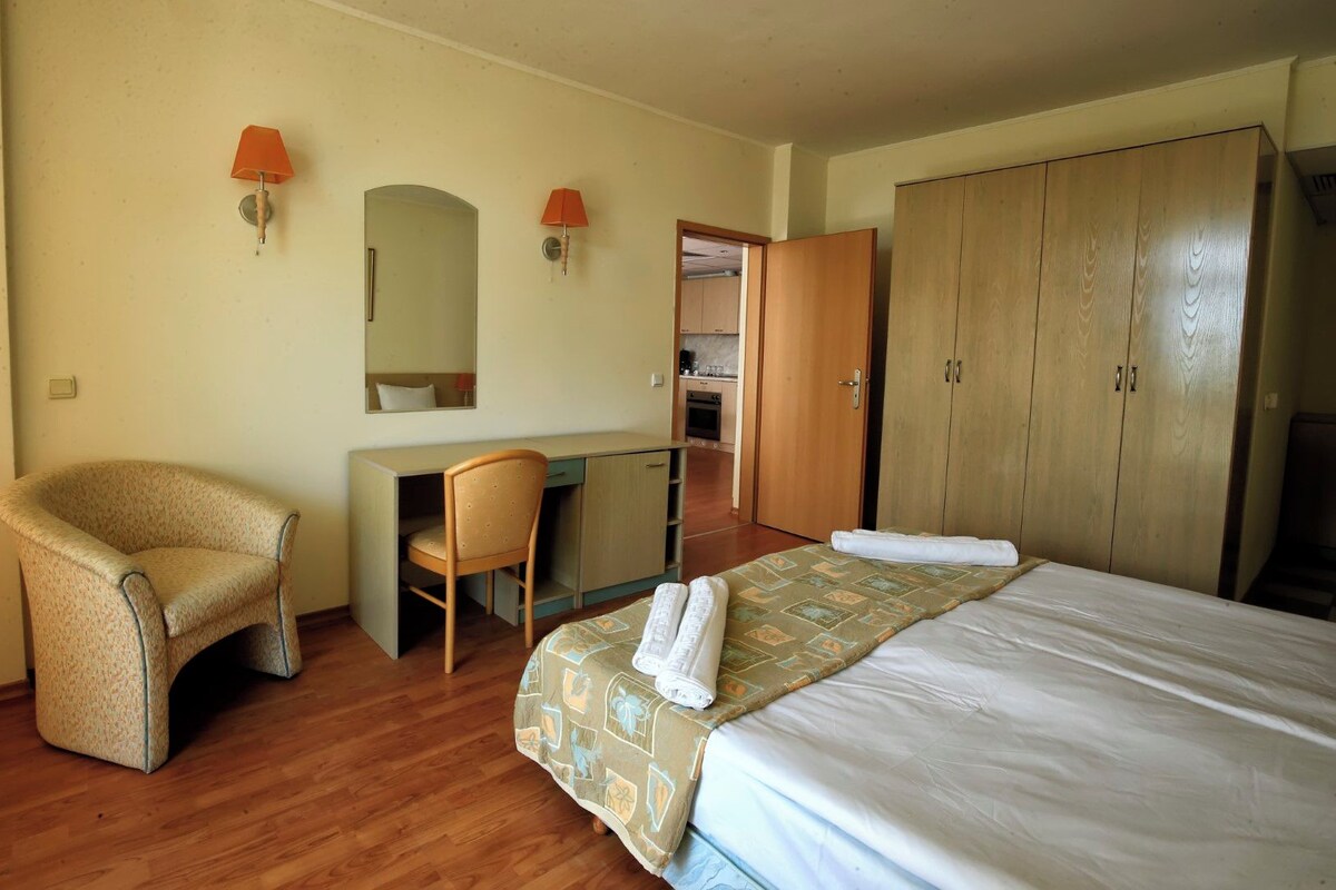 Une chambre d’hôtel comprenant un lit, un bureau, une chaise, une armoire et un miroir.