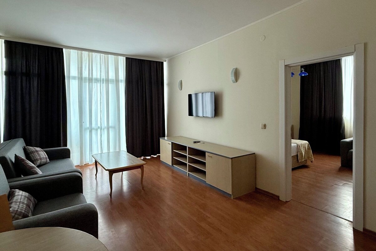Una sala de estar moderna con un sofá, un televisor, una mesita y suelo de madera.