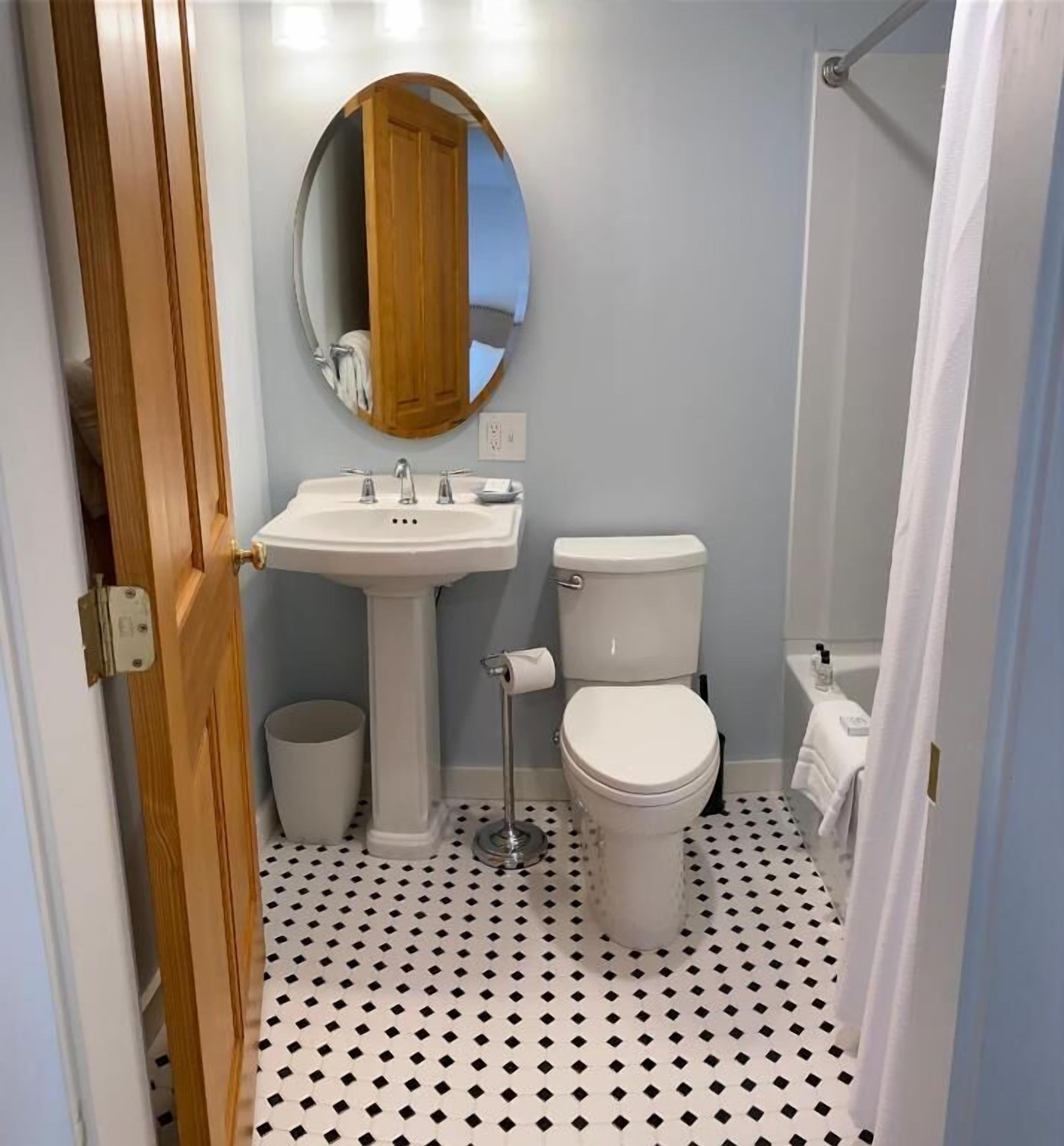 Une salle de bain avec un lavabo blanc, des toilettes et un miroir au-dessus du lavabo.