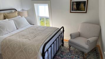 Une chambre à coucher avec un lit, une chaise, une fenêtre et un tableau encadré au mur.