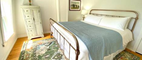 A bedroom with a bed, a dresser, a lamp, and a framed picture on the wall.