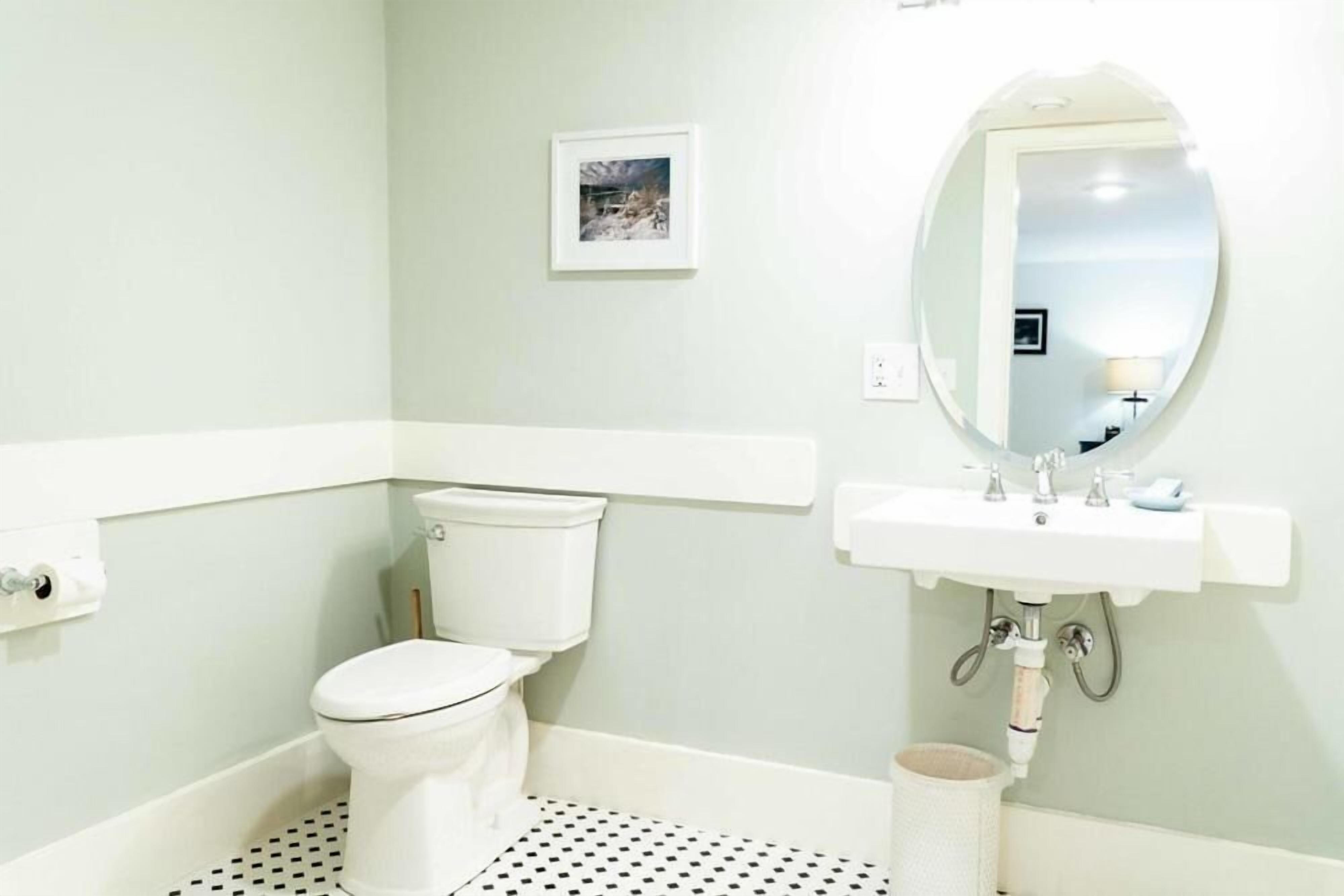 A bathroom with a toilet, sink, and mirror.