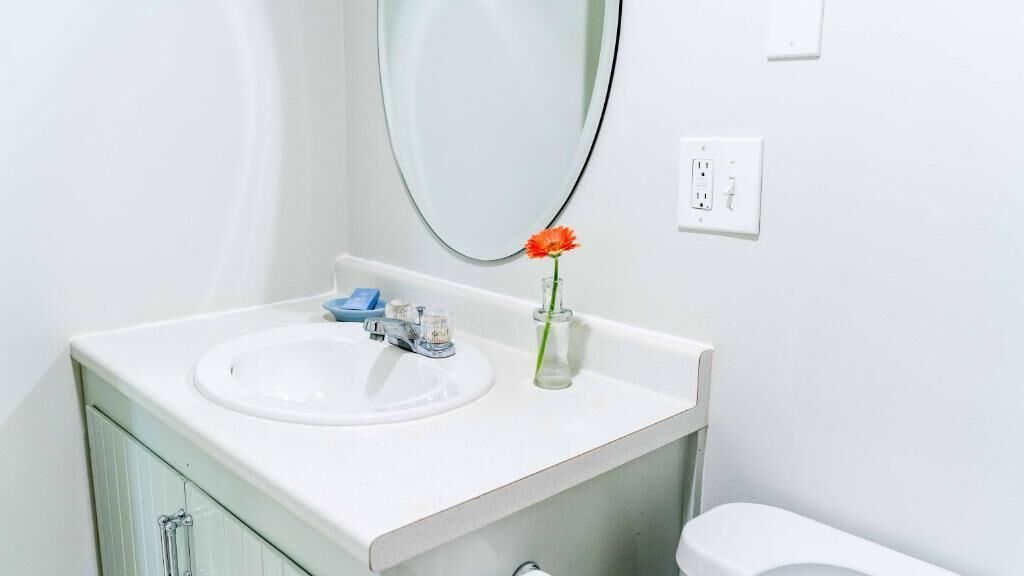 A bathroom with a white sink, mirror, and toilet.