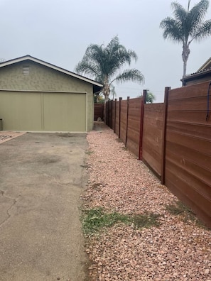 A residential garage with a gravel driveway and a wooden fence.