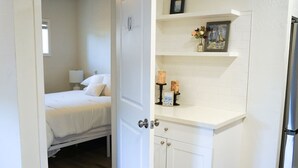Ein Schlafzimmer mit einem Bett, einem Nachttisch, einer Kommode und einem Regal mit Dekoration.