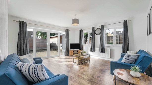 A living room with a blue sofa, a coffee table, and a TV. - Modern Comfort |4BR House for 11| Central & Quite (Essex)
